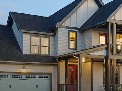 Typical mid-class home with light gray Mastic siding during dusk